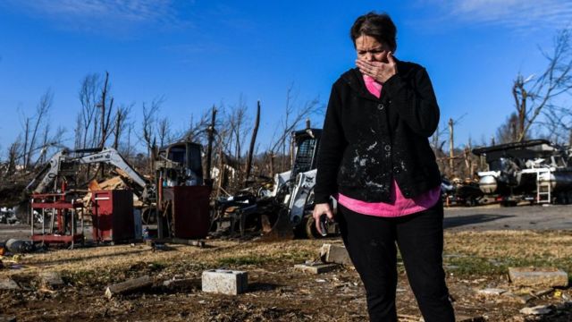 A woman cries in front of a pile of rubbish from a hurricane that has hit five states in the United States.