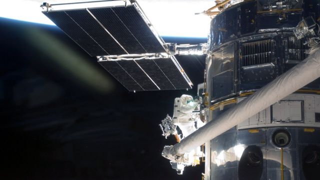 An astronaut makes repairs to the International Space Station