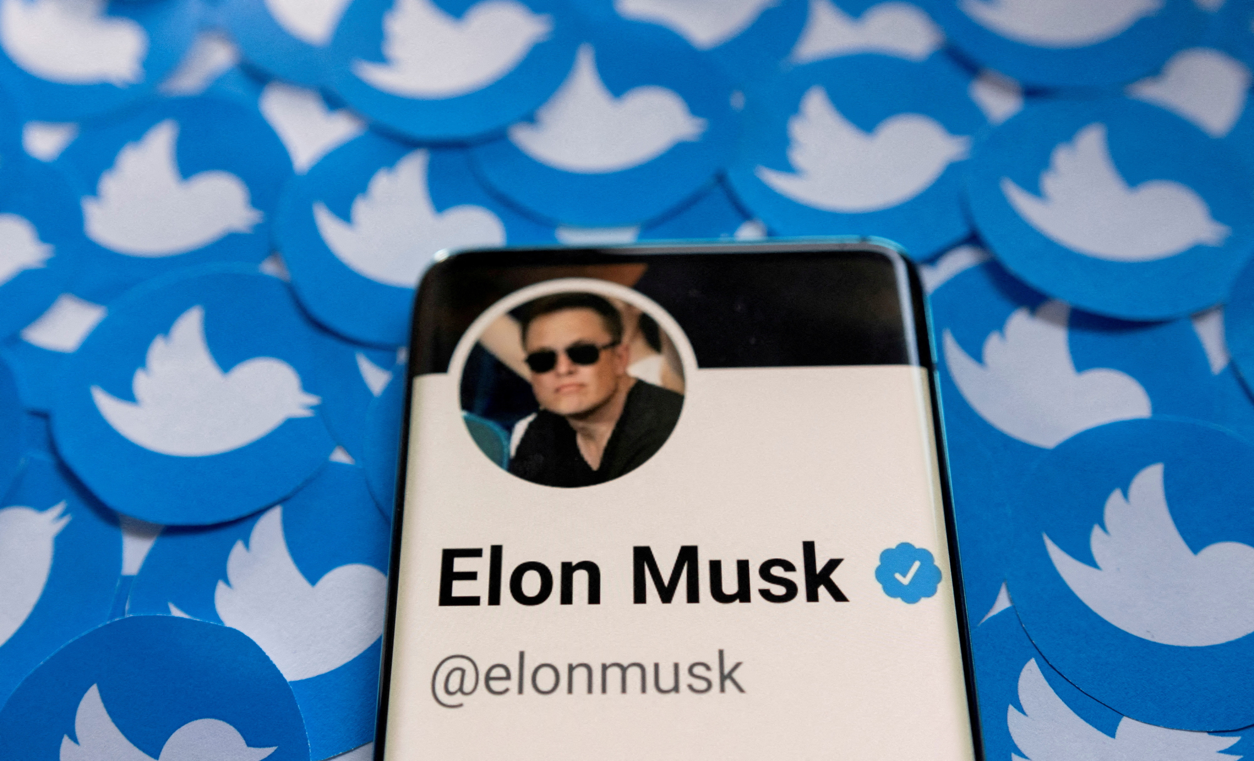 FILE PHOTO: Elon Musk's Twitter profile is seen on a smartphone placed over a printed Twitter logo in this April 28, 2022 photo caption.  REUTERS/Dado Ruvic/Illustration/File Photo